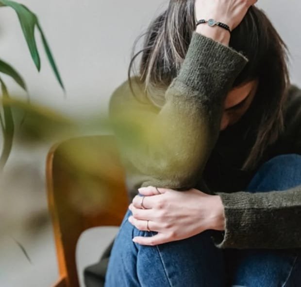 Mulher sentada com postura de tensão emocional, representando os efeitos da ansiedade feminina.